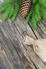 Small bag of burlap and a branch of green spruce against the background of wooden table. 