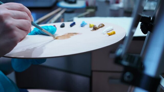 a girl mixes oil paints on a wooden palette for drawing.