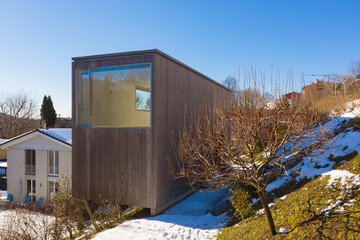 Small wooden house, minimal, located in Switzerland. Winter season, some snow on the sides