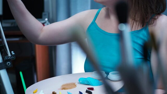 a talented artist draws with a brush on canvas. the view from behind the brushes, a smooth transition from the palette to the artist's face.