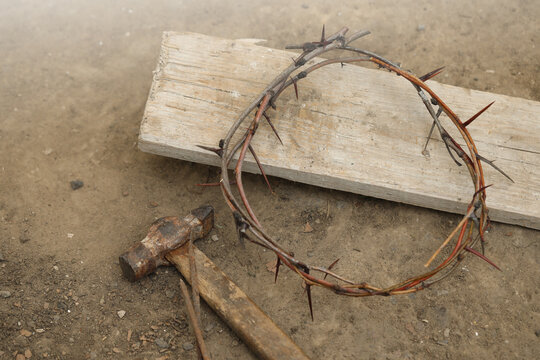 Crown of thorns, hammer with nails and wooden plank on ground, above view. Easter attributes