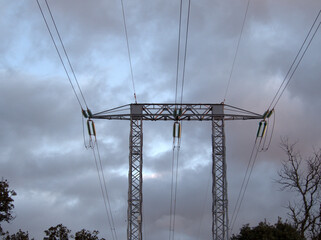 In the evening and on a very cloudy day, a large outdoor electricity tower, necessary for the transport of energy