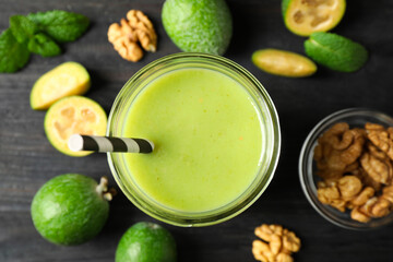 Fresh feijoa smoothie in glass on black wooden table, flat lay