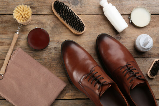 Flat lay composition with shoe care accessories and footwear on wooden background