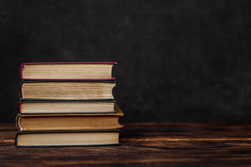 a stack of hardcover books on a dark background copy space