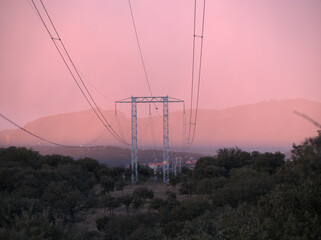 In the evening and on a very cloudy day, a large outdoor electricity tower, necessary for the transport of energy