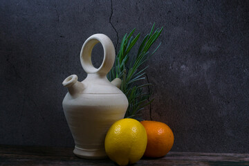 View of lemon, orange, vase ceramics, and gre against a concrete wall