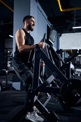 Bearded sportsman sitting at the fitness equipment