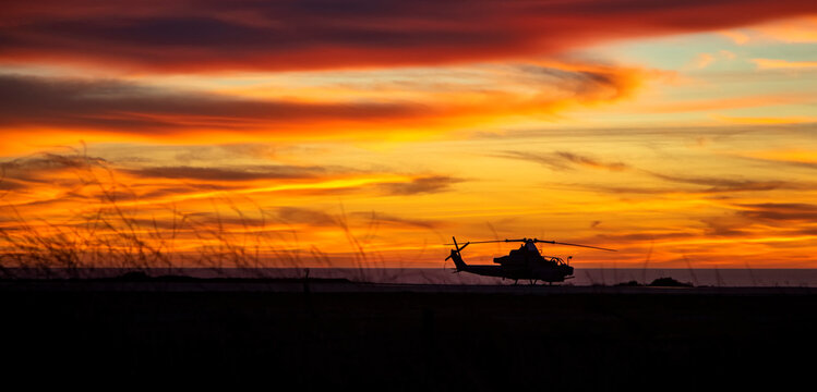 Silhouette of an attack helicopter at against a dramatic cloudy sky at sunset or sunrise