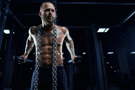 Man posing on parallel bars in gym.