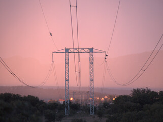 In the evening and on a very cloudy day, a large outdoor electricity tower, necessary for the transport of energy