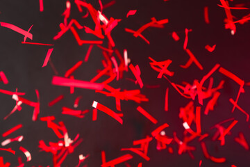 Shiny red confetti falling down on dark background