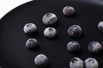 Frozen blueberries on a black plate, frozen berries, ingredient