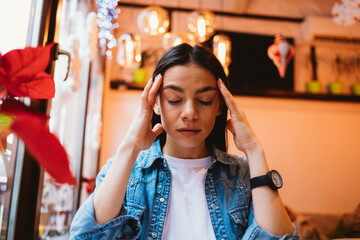 Portrait of a young tired woman in a denim jacket holds her head