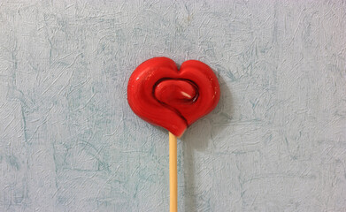 Lollipop on a stick in the shape of a red heart, a sweet treat for Valentine's Day. High quality photo