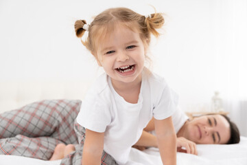 adult mother play with little active daughters at home, having fun, leisure activity with children.