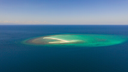 Seascape, white sand island. Atoll near the island of Camiguin, Philippines, aerial view. Atoll with a white island. Beautiful coral reef in the blue sea, top view.