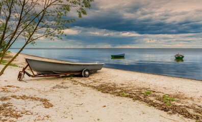 Naklejka na ściany i meble Anchored fishing boat on sandy beach of the Baltic Sea