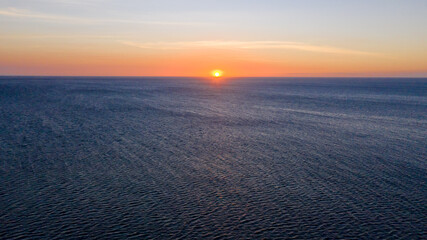 Sunset over the sea in clear weather, view from above.  The sun sets over the horizon over the sea.