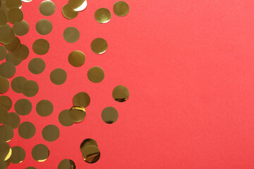 Shiny golden confetti on red background, flat lay. Space for text
