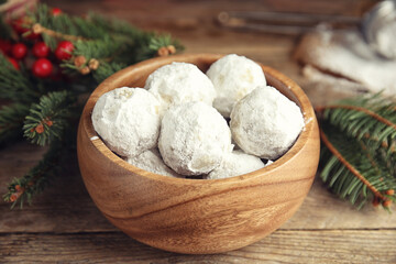 Fototapeta na wymiar Tasty snowball cookies in bowl and Christmas decorations on wooden table