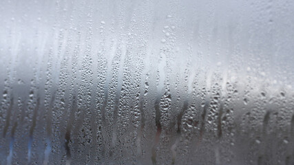 Background of condensation of water droplets on glass, humidity and fog behind glass, bad weather,...
