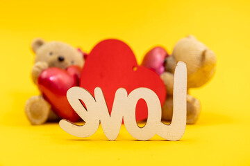 Couple of teddy bears toys and the word love from wooden letters, red hearts. Valentine day concept. Postcard template.