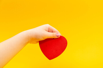 Red heart in teenager hand on yellow. Valentine day concept.