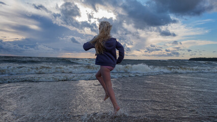Fototapeta na wymiar A girl runs into the waves of a raging sea
