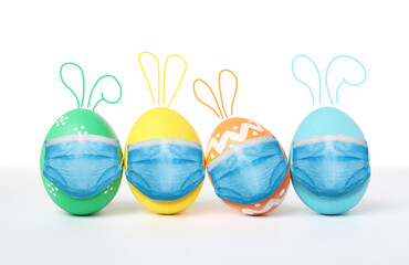 COVID-19 pandemic. Colorful Easter eggs with cute bunny ears in protective masks on white background