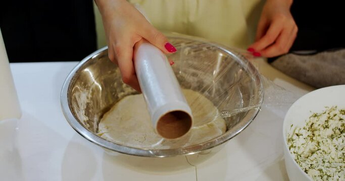 Cover food with thin plastic wrap for food in the kitchen. Slow motion.
