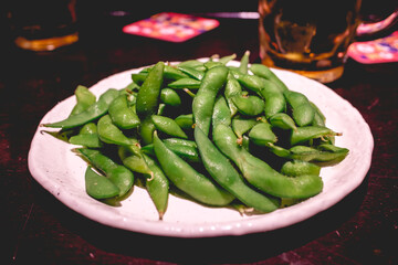 Japanese Edamame green beans (with salt and butter) on a white plate, and a beer, Tokyo, Japan