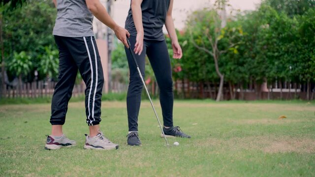 Asian couples playing golf together in the course, difficult time stay together in the family outdoor concept of green park.