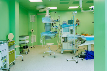 Fototapeta na wymiar Interior of operating theatre with green walls for birthing of pregnant women, birth Surgery, natural birth, giving birth with caesarian operation. Modern equipment in operating room. Nobody.