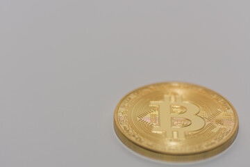 one single golden bitcoin lying on a gray background right bottom