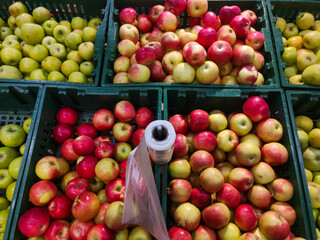 juicy ripe apples of different varieties are sold at retail in the mall on a shelf in plastic boxes