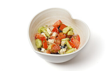 Vegetable salad with cucumber, tomato, olive, onion, lettuce and feta cheese in white ceramic bowl