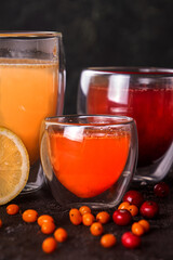 Glasses of fruit drink tea of ginger, lemon, sea buckthorn, lingonberry.  Fresh fruits and berries. Black background