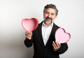 Portrait of a smiling man in suit with a heart-shaped box on white background