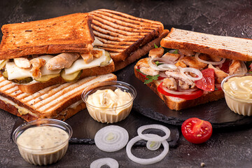 Ingredients and sandwiches with chicken meat, cherry tomato, onion and chicken meat, marinated cucumbers, mozzarella cheese on  black background. copy space