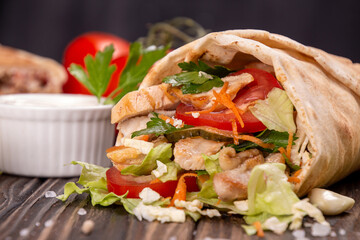 Popular arabic turkish fastfood doner shawarma roll with meat and vegetables and ingredients on wooden background. top view