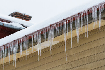 Long transparent icicles on cornice of old wooden building