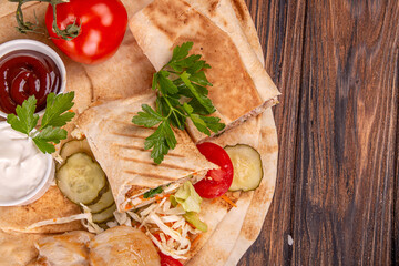 Popular arabic turkish fastfood doner shawarma roll with meat and vegetables and ingredients on wooden background. top view