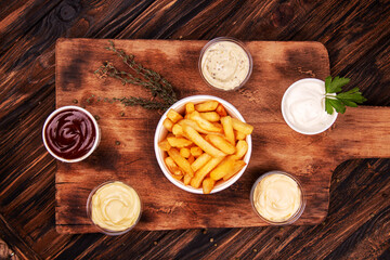 Obraz na płótnie Canvas French fries chips potato and sauces on wooden background. top view