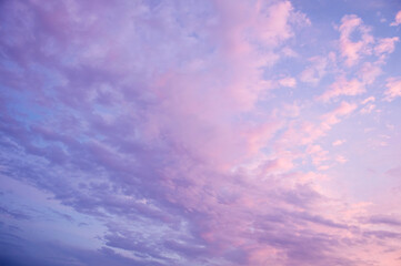 Beautiful blue sky background. Soft white clouds at sunset. Many pink, magenta and orange tones and patterns of clouds