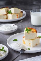 Cottage cheese casserole with raisins and cup of milk on wooden grey background. Cottage cheese casserole..