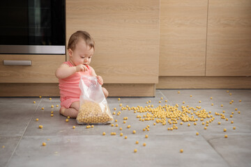 Cute baby making mess with bag of cereal