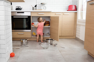 Rear view of toddler making mess in kitchen cabinet