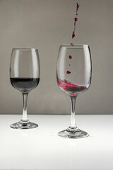 Red wine is poured from a bottle into a glass on a blurred background, close-up.