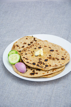 Aloo parotha in a white plate with onion, salad and broccoli fry with raita . An indian healthy breakfast